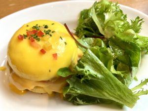 Eggs Benedict on a white plate, served with a reel salad.