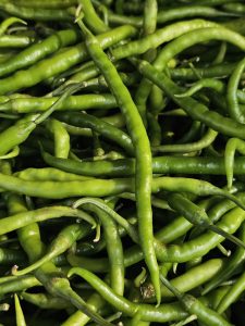 A close-up of fresh green chillies, showing their bright colour and natural shine. Captured at a market in Asalpha, Mumbai. 