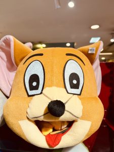 A close-up of a large plush head costume resembling the cartoon character Jerry Mouse, with wide eyes, big pink ears, and a black nose.
