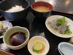 A black bowl of steaming white rice sits next to a red bowl of miso soup with a sprinkle of green herbs.
