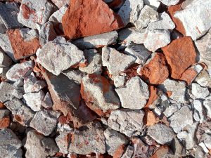 
A close-up view of a pile of mixed gravel stones, featuring a combination of gray, white, and reddish-brown pieces. 