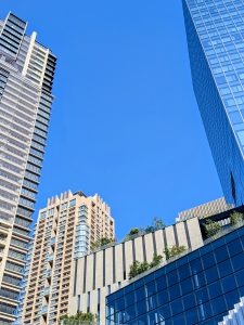 A view of modern skyscrapers against a clear blue sky, featuring a mix of glass and concrete structures.