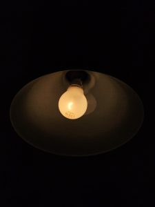 A single warm bulb glowing inside a dark lampshade, casting a soft, calm light. A simple moment captured beautifully at BKC, Mumbai. 