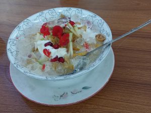 A bowl of Falooda, a popular Dhaka dessert with crushed ice, fruits, and red syrup.
