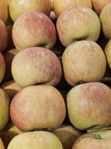 Fresh light-red apples stacked closely together. Their soft, red, and yellow colors, along with their smooth skin, are clearly visible. Captured from a market in Kozhikode, Kerala. 