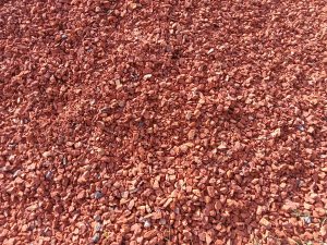 A close-up of a mound of reddish-brown crushed red bricks with unevenly shaped pieces of varying sizes.