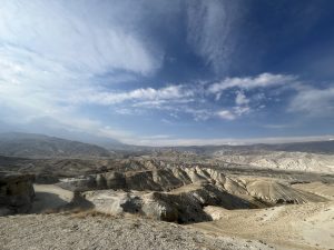 A panoramic view of a rugged, arid landscape featuring rolling hills and valleys.