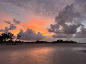Beautiful sunrise at Kuakata Beach, Bangladesh, with golden light on wet sand and dramatic morning clouds.