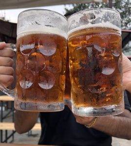 Two large, frosty beer mugs are clinking together in celebration. 