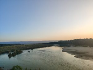 A serene landscape featuring a winding river surrounded by lush greenery and gentle hills.