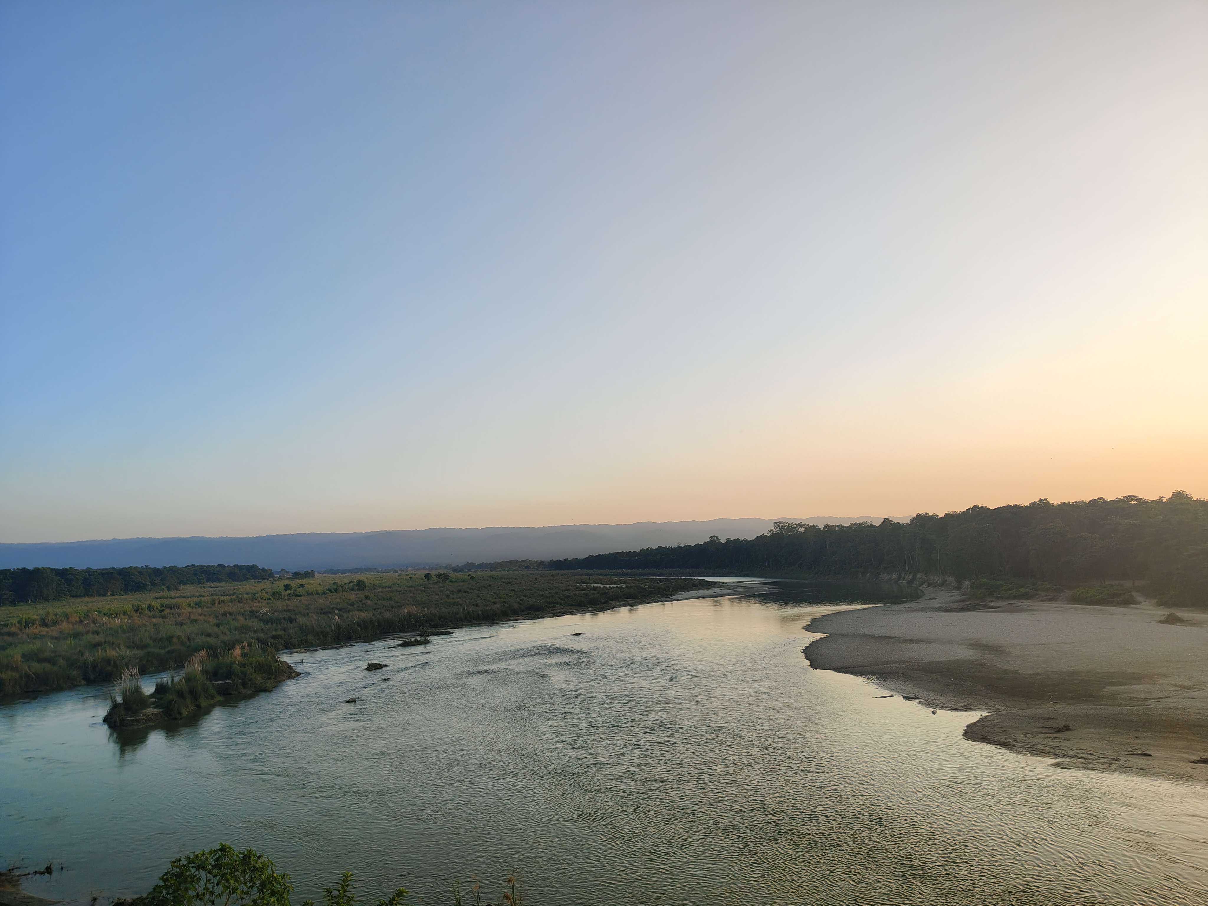 A serene landscape featuring a winding river surrounded by lush greenery and gentle hills.