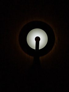A glowing round wall light shines softly in the dark, creating a simple and calm mood. Captured in Perumanna, Kozhikode.