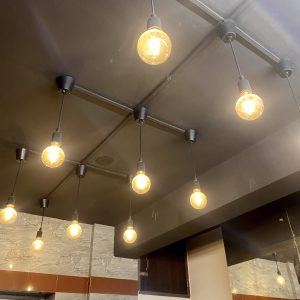Ceiling with hanging Edison-style light bulbs, casting a warm glow in an industrial setting. The ambiance is cozy and inviting, with a modern touch.