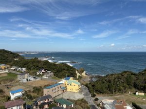 A scenic coastal view featuring a mix of lush green hills and rocky shores, with the ocean gently lapping at the edges. 