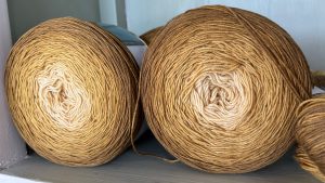 Closeup of two rolls of yarn sitting on a shelf.
