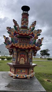 A colorful ornate structure resembling a traditional pagoda, adorned with intricate dragon sculptures and vibrant decorations. 
