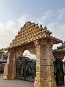 An intricately designed entrance gate featuring ornate carvings and traditional architectural elements, with a large black metal gate in the center. 