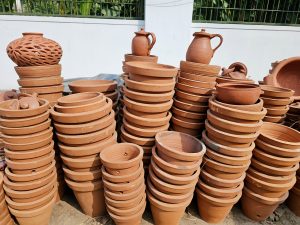 Stacks of terracotta plant pots displayed in sunlight at a roadside shop in Kozhikode, Kerala. The warm earthy colors and shapes show traditional clay work used for gardening and home use. 