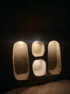 A dimly lit interior featuring three arched niches with a textured, beige surface.