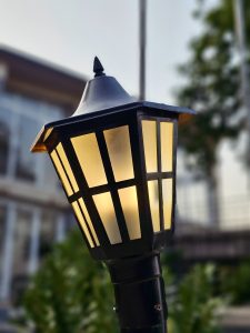 A warm, glowing outdoor lamp near the Elephanta Caves, Mumbai. The soft yellow light shines through the black metal frame. 