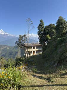 A scenic mountain landscape with a stone building surrounded by lush greenery and trees.