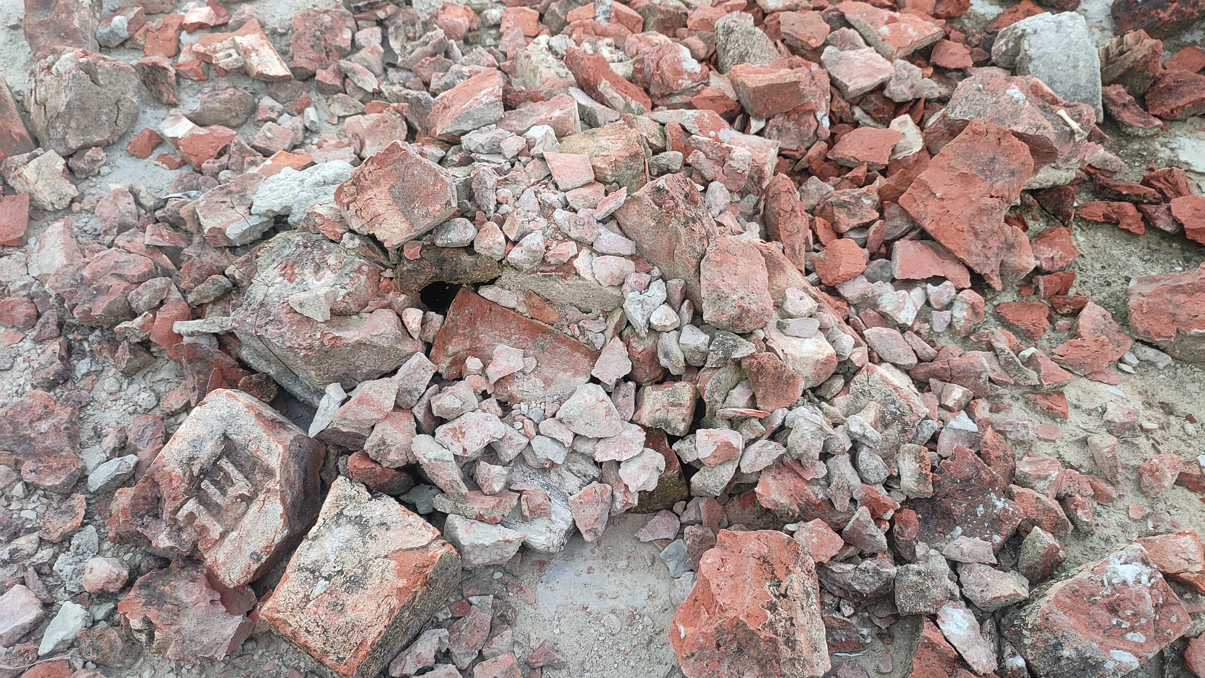 A close-up view of a pile of broken red bricks and rubble scattered across a surface.