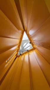 The photo looking up at the Umeda Sky Building in Osaka, Japan, through the yellow sculpture in front of it.