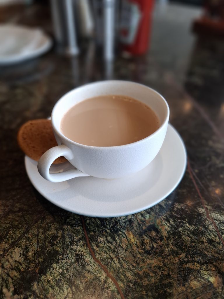 A mug of African tea with a cookie on the side.