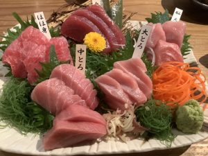 A beautifully arranged platter of sashimi featuring various cuts of fresh fish, primarily tuna, displayed on a bed of green seaweed