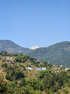 A scenic landscape featuring rolling green hills with scattered houses in various colors. 