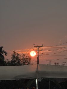 A sunset is partially visible behind utility poles and power lines.