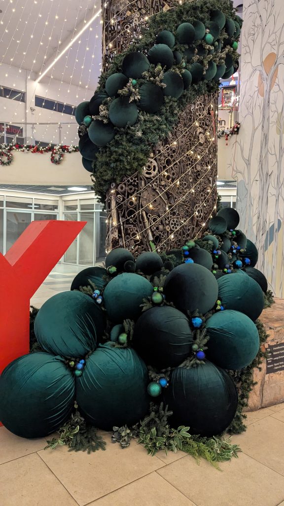 A decorative display featuring large, plush green balls arranged at the base of a metallic structure.
