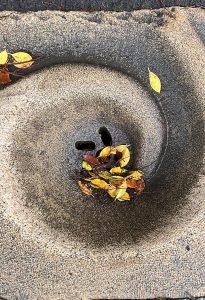 A close-up of a circular, textured surface with two drainage holes in the center, surrounded by a swirl pattern.