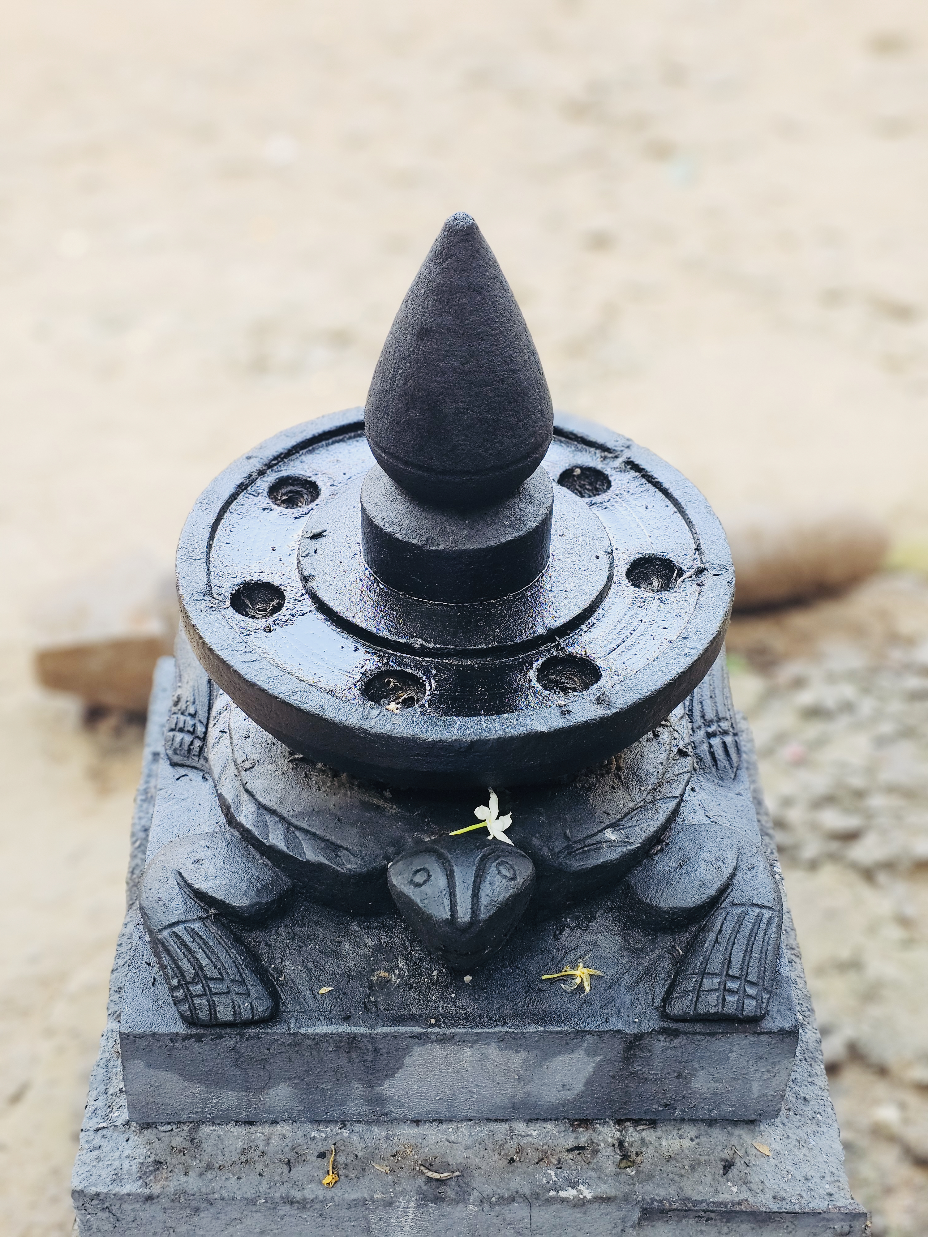 A close-up view of a traditional black stone lamp placed on a carved tortoise base, showing fine details and a calm, sacred presence. Taken in Kozhikode, Kerala, this photo reflects local temple traditions, devotion, and timeless spiritual practices.