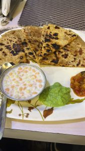 comforting Indian Paratha Thali served with soft, golden-brown parathas—crispy on the outside and fluffy inside. Paired with cool, creamy dahi to balance the spices, a burst of flavor from tangy chutney, and a punch of traditional pickle for that classic desi kick.