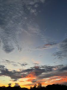 A stunning sunset captured from an airplane window, featuring a blend of warm colors spreading across the sky.