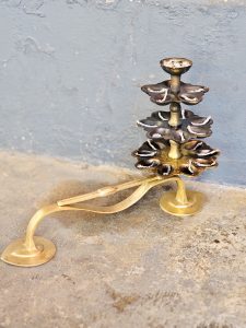A classic multi-tier brass oil lamp with cotton wicks arranged for lighting during prayers. The warm metal tones reflect Kerala&rsquo;s temple traditions, captured outdoors in Kozhikode, Kerala. 