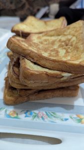 A close-up image of a stack of golden brown toasted bread slices on a plate. 
