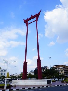 Photo of Thailand's Giant Swing, Sao Ching Cha. It is a 21.15 meter tall swing-shaped structure and a prominent landmark. The swing is red, in contrast with the sky's blue background.