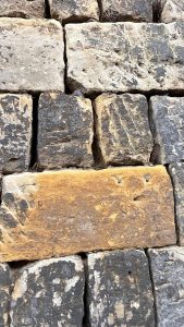 A close-up view of a stone wall composed of variously sized stones in shades of gray and brown.
