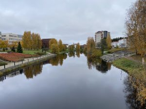 Autumn view of Seinäjoki River, Finland, with golden trees, calm reflections, and riverside buildings.