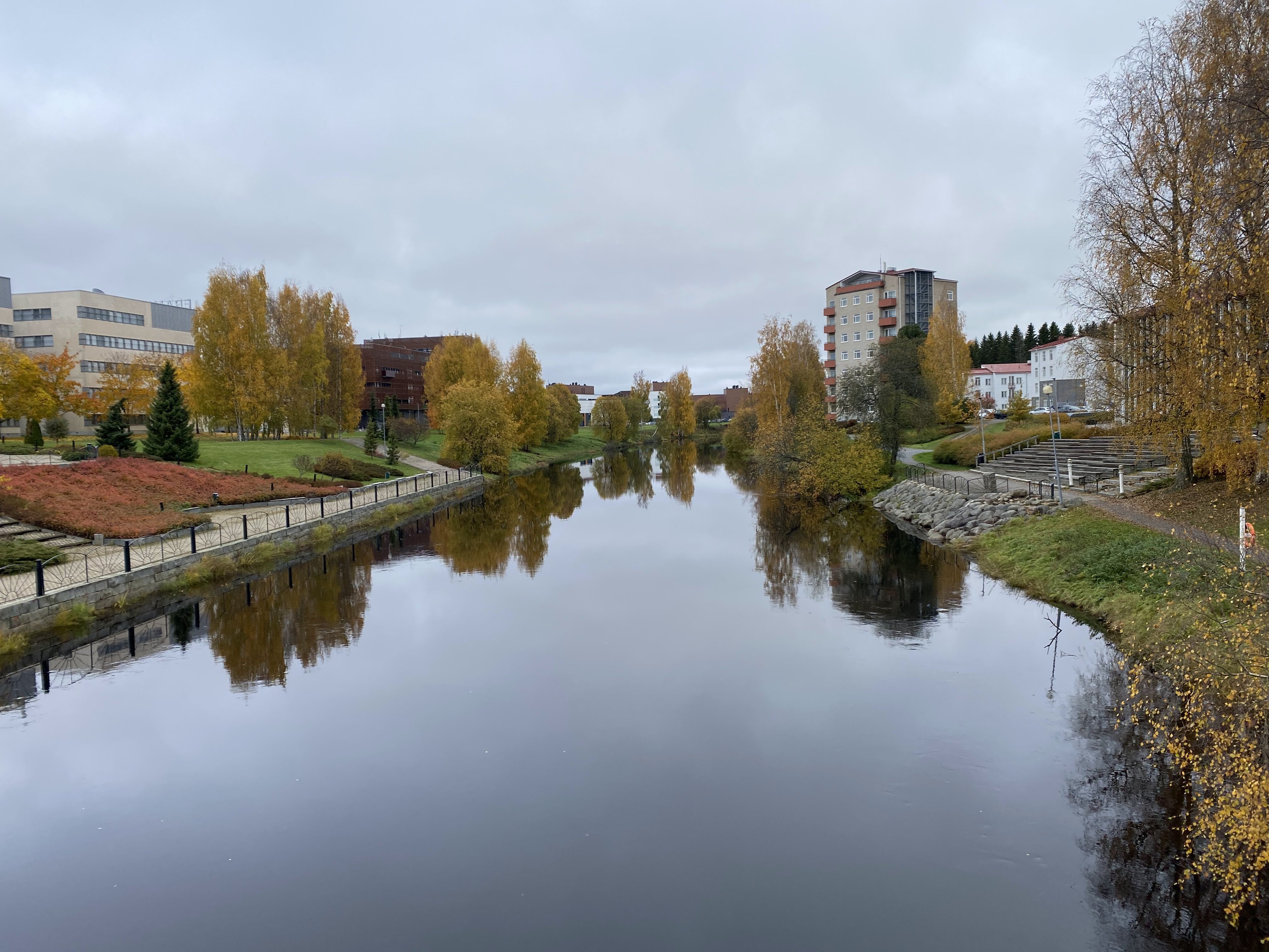 Autumn view of Seinäjoki River, Finland, with golden trees, calm reflections, and riverside buildings.