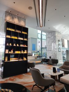 A scene of a hotel lobby with sunlight pouring in from a large window.