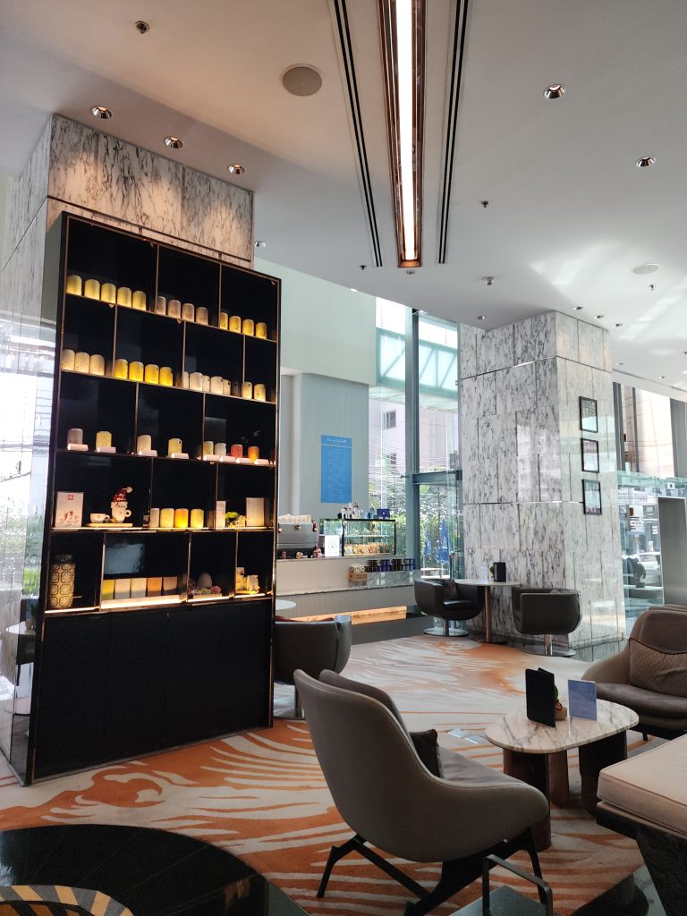 A scene of a hotel lobby with sunlight pouring in from a large window.