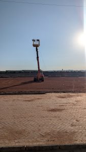 A crane in a brown field on an open space on a nice sunny day with a view of a clear sky above it.