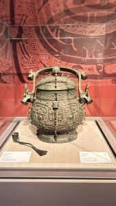 A bronze ritual vessel with a round body and elaborate designs, featuring two ornate handles shaped like mythical creatures. 