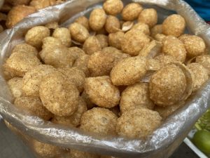 A close-up of a bag filled with golden, crispy Golgappa (Pani Puri) snacks.
