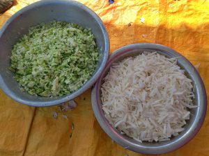 Two bowls are placed on a textured orange surface. The bowl on the left contains finely chopped green vegetables, including cucumber and radish.