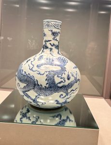 A blue and white porcelain vase with a bulbous body and a slender neck, featuring intricate designs of a dragon and clouds.