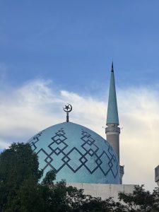 A mosque featuring a large, turquoise dome adorned with geometric patterns, topped with a prominent crescent moon and star emblem. Masjid Sultan Ismail, Universiti Teknologi Malaysia.